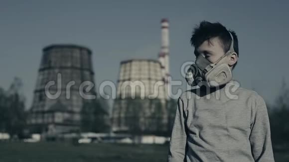 戴着面具的青少年男孩在防毒面具呼吸器上对工业吸烟管采取特写空气污染视频的预览图