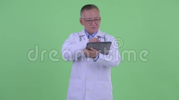 快乐成熟的日本男医生用数码平板电脑思考视频的预览图