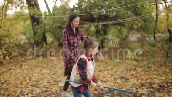 妈妈和女儿正在院子里打扫秋天的树叶视频的预览图