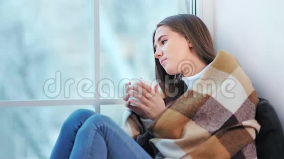 忧郁的年轻迷人的女人在家享受周末坐在窗边喝咖啡视频的预览图