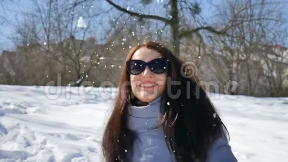 戴着深色太阳镜的美丽成年女孩的冬季肖像享受阳光明媚的一天等待春天的时光视频的预览图