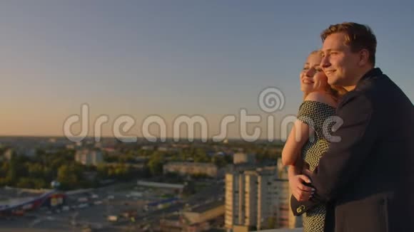 可爱的甜蜜幸福夫妇坐在屋顶顶部令人惊叹的日落景色在城市城镇他们彼此相爱视频的预览图