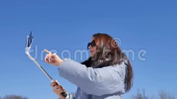 有魅力的黑发女人戴着太阳镜用智能手机自拍在户外呆着视频的预览图