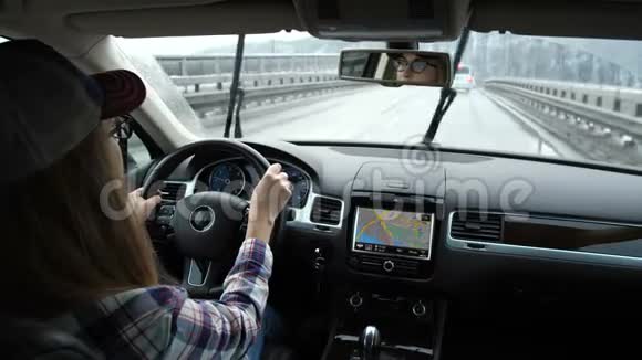 雨天那个女孩在开车汽车在桥上行驶蛇会起作用眼睛在镜子里是可见的4K视频的预览图
