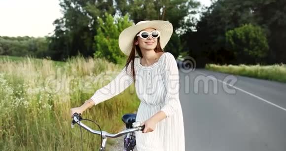 在乡村路上骑着自行车走路的女人视频的预览图