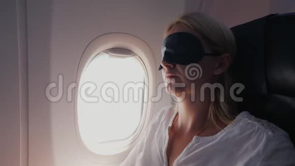 一位中年妇女正睡在一架客机的机舱里一条深色的绷带穿在她的眼前视频的预览图