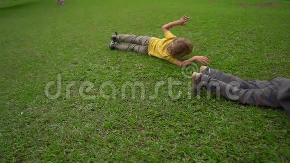 两个小男孩在草坪上玩得很开心他们滚下山坡视频的预览图