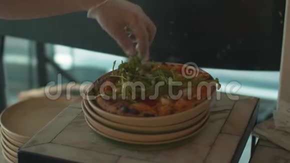 厨师用手戴乳胶手套把阿鲁古拉放在披萨上视频的预览图