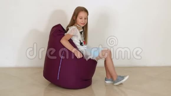 可爱的小女孩坐在紫豆袋沙发上作为客厅慢动作视频的预览图