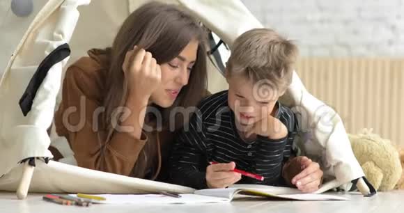 一家人的母亲和儿子在相册里一起画铅笔的肖像躺在蒂皮里视频的预览图