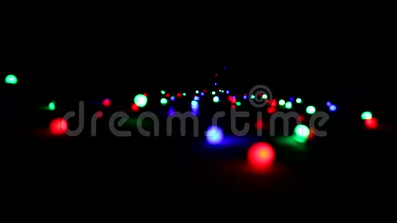 一个花环在黑暗中躺在地板上闪烁着五颜六色的明亮灯光圣诞节和新年的气氛视频的预览图