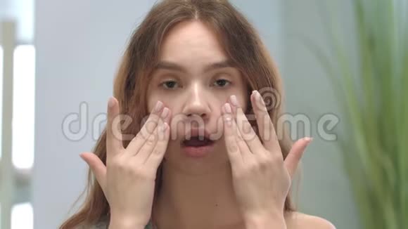 年轻女人做面部按摩的脸模特儿模仿体操视频的预览图