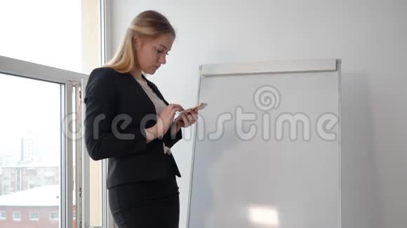 商务女性在会议室的挂图上使用手机视频的预览图