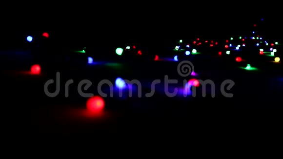 一个花环在黑暗中躺在地板上闪烁着五颜六色的明亮灯光圣诞节和新年的气氛视频的预览图