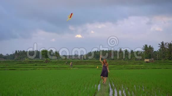 一个带着风筝的年轻女子慢镜头穿过一个美丽的大稻田视频的预览图
