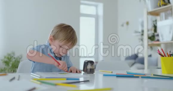 这个男孩用一支彩色铅笔在客厅的桌子旁画画视频的预览图