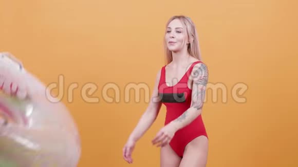 性感的金发女人穿着一件泳衣玩游泳圈视频的预览图