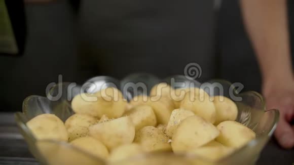男人在黑暗的厨房里把橄榄油倒在土豆上视频的预览图