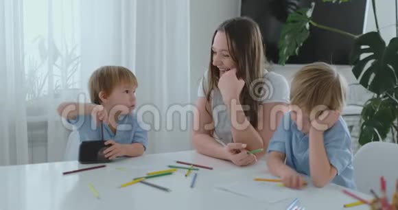 妈妈坐在桌子旁两个儿子坐在厨房的桌子旁男孩正在磨一支彩色铅笔这就是视频的预览图