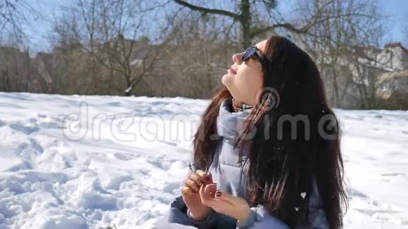 漂亮的女孩戴着镜子太阳镜享受阳光明媚的一天在户外等待春天的时光视频的预览图