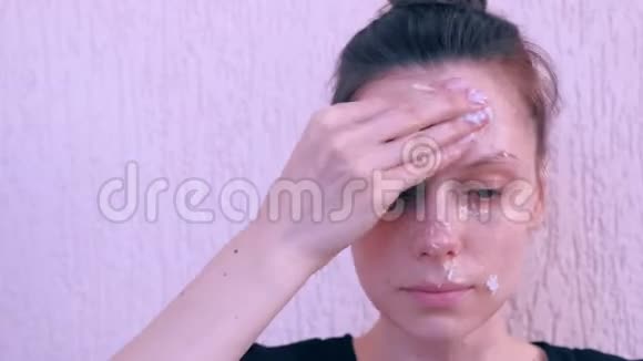 女人正在用椰子壳在脸上涂上新鲜的自制椰子面膜视频的预览图