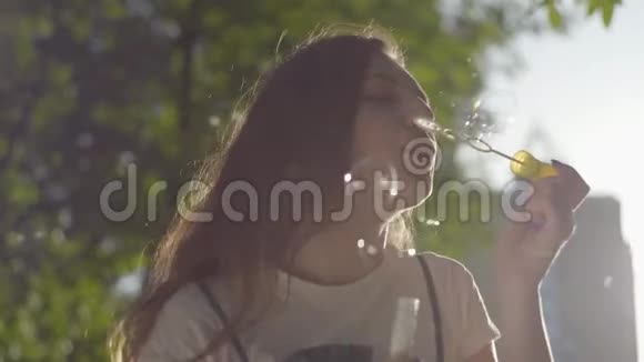 公园里少女在镜头前吹肥皂泡的肖像可爱的年轻女人独处视频的预览图