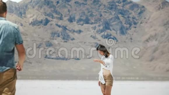 后景浪漫情侣牵着手走向犹他州盐沙漠中部的白色平地视频的预览图