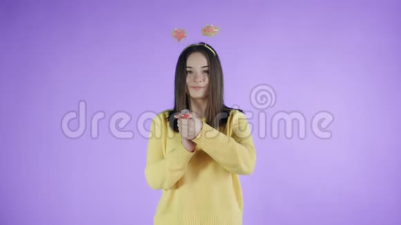 年轻女子在紫色背景上爆炸纸屑饼干视频的预览图