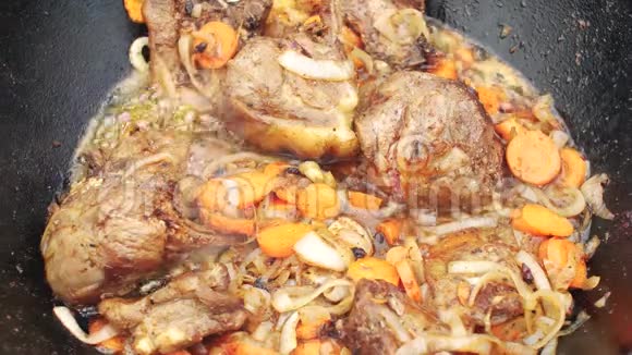 洋葱和胡萝卜的一小块羊肉在火上用煮沸的油煎作为准备传统的视频的预览图