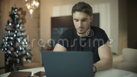 严肃的男人在圣诞节家里打电话在电脑桌上工作的男人视频的预览图