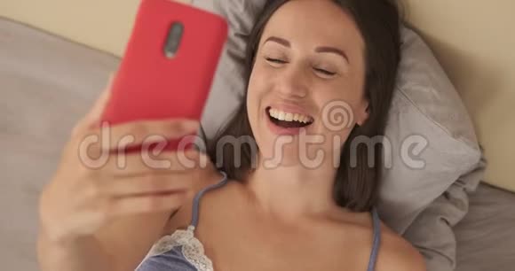 女人一边笑一边用手机聊天视频的预览图