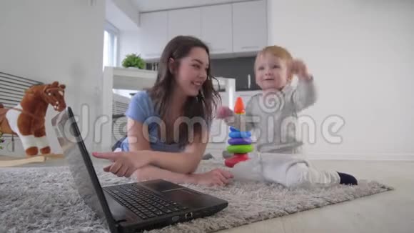 母子关系快乐的妈妈和可爱的小男孩一起在笔记本电脑上看动画片拍拍躺在上面的手视频的预览图