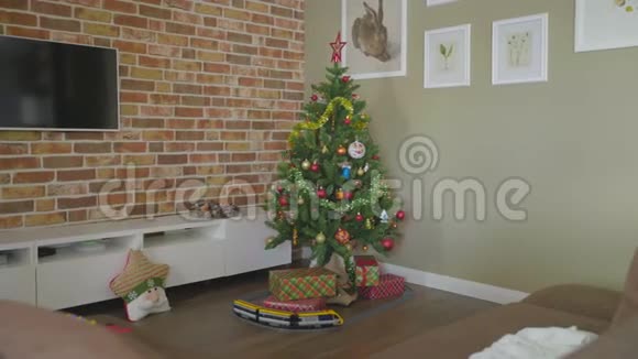 带有装饰光的圣诞树地板上的礼品盒和玩具蒸汽机视频的预览图
