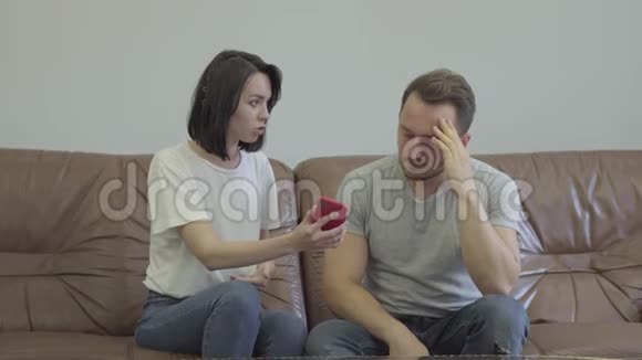 愤怒的女人对悲伤的丈夫大喊大叫用他在家的情人的信息显示手机问题视频的预览图