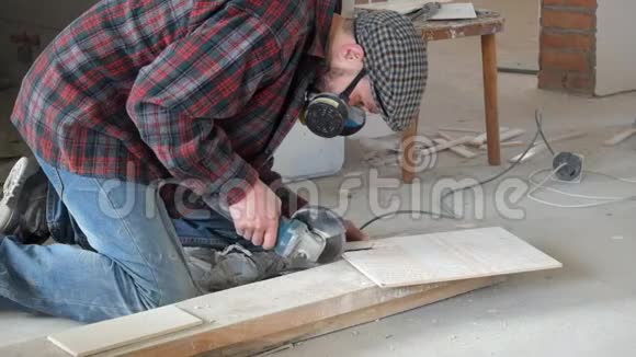 穿格子衬衫和呼吸器的工人用角磨机切割瓷砖视频的预览图