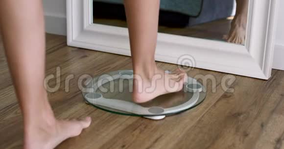 女人光着脚站在秤上在家里特写测量体重视频的预览图