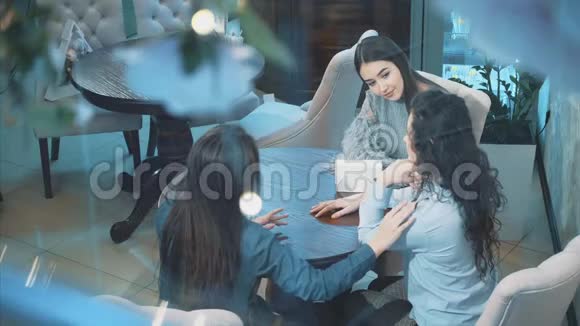 三个年轻漂亮的女孩坐在咖啡馆里在这段时间女朋友交流有漂亮的黑色长发之后视频的预览图