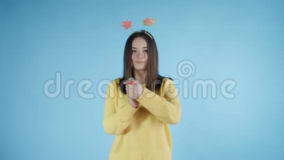 年轻女子在蓝色背景下爆炸纸屑饼干视频的预览图