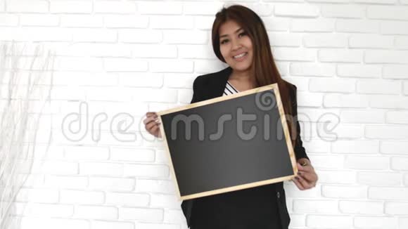 年轻快乐的漂亮女商人一边拿着黑板一边微笑视频的预览图
