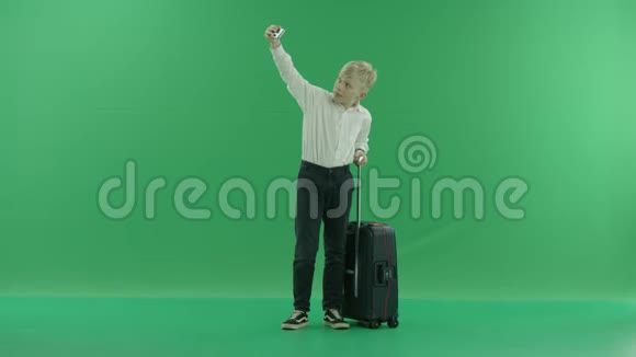 一个穿校服的金发小男孩正拿着一个手提箱在手机上自拍他反对一个视频的预览图
