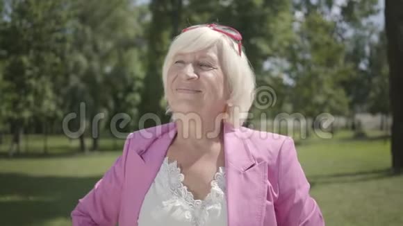 成熟的微笑女人看着相机微笑站在夏天的公园户外休闲成熟的白种人女士休息视频的预览图