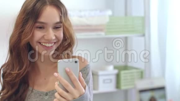 微笑的女人在浴室镜子手机上拍照快乐女孩视频的预览图