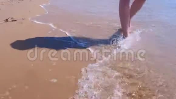 赤脚女游客在海水中漫步沙滩沙滩双腿特写视频的预览图