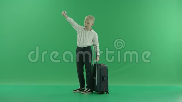 一个穿校服的金发小男孩正拿着一个手提箱在手机上自拍他反对一个视频的预览图