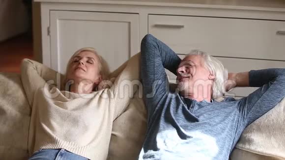 平静的老夫妇一起在柔软舒适的沙发上放松视频的预览图