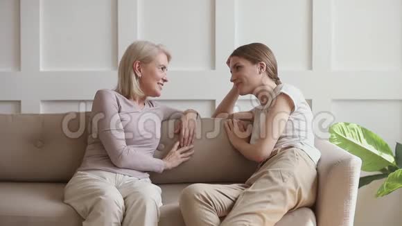 快乐的成年女儿和成熟的母亲在家里说闲话视频的预览图