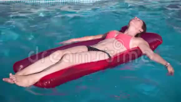 年轻快乐的女人在晴天在蓝色游泳池里放松充气游泳池玩具视频的预览图