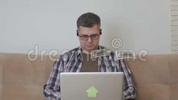 一个中年男子坐在沙发上手提电脑美元在贬值视频的预览图