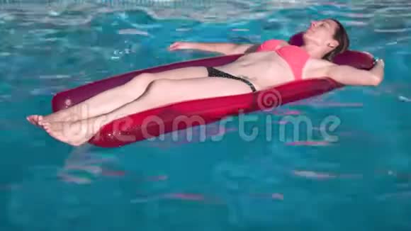 年轻快乐的女人在晴天在蓝色游泳池里放松充气游泳池玩具视频的预览图