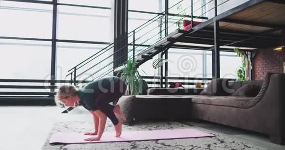 运动的女士在家里在垫子上练习瑜伽她做手臂平衡练习和伸展身体太棒了视频的预览图
